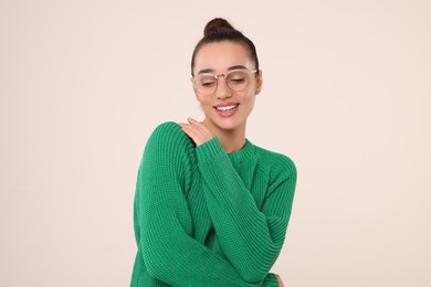 Beautiful young woman in stylish warm sweater on light grey background