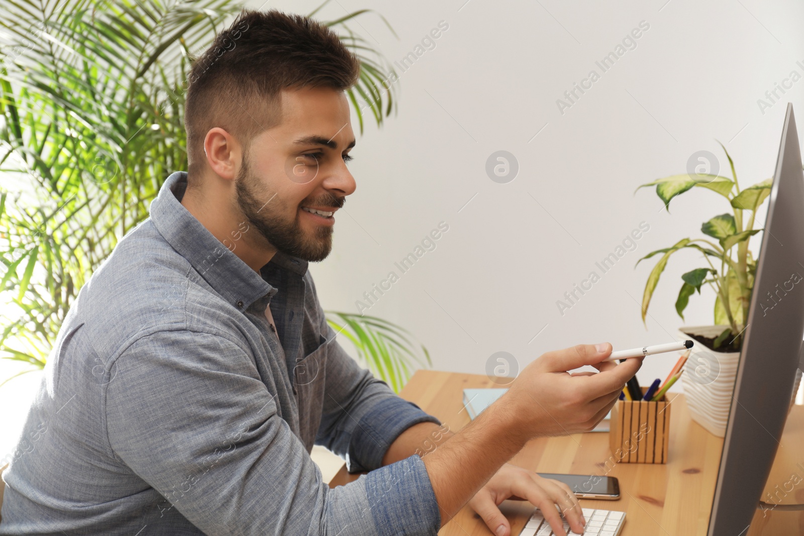 Photo of Young man using computer at table in office