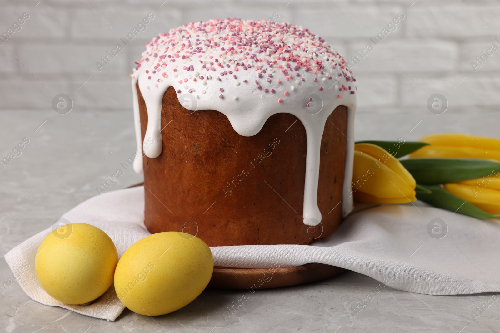 Photo of Tasty Easter cake, decorated eggs and flowers on grey table