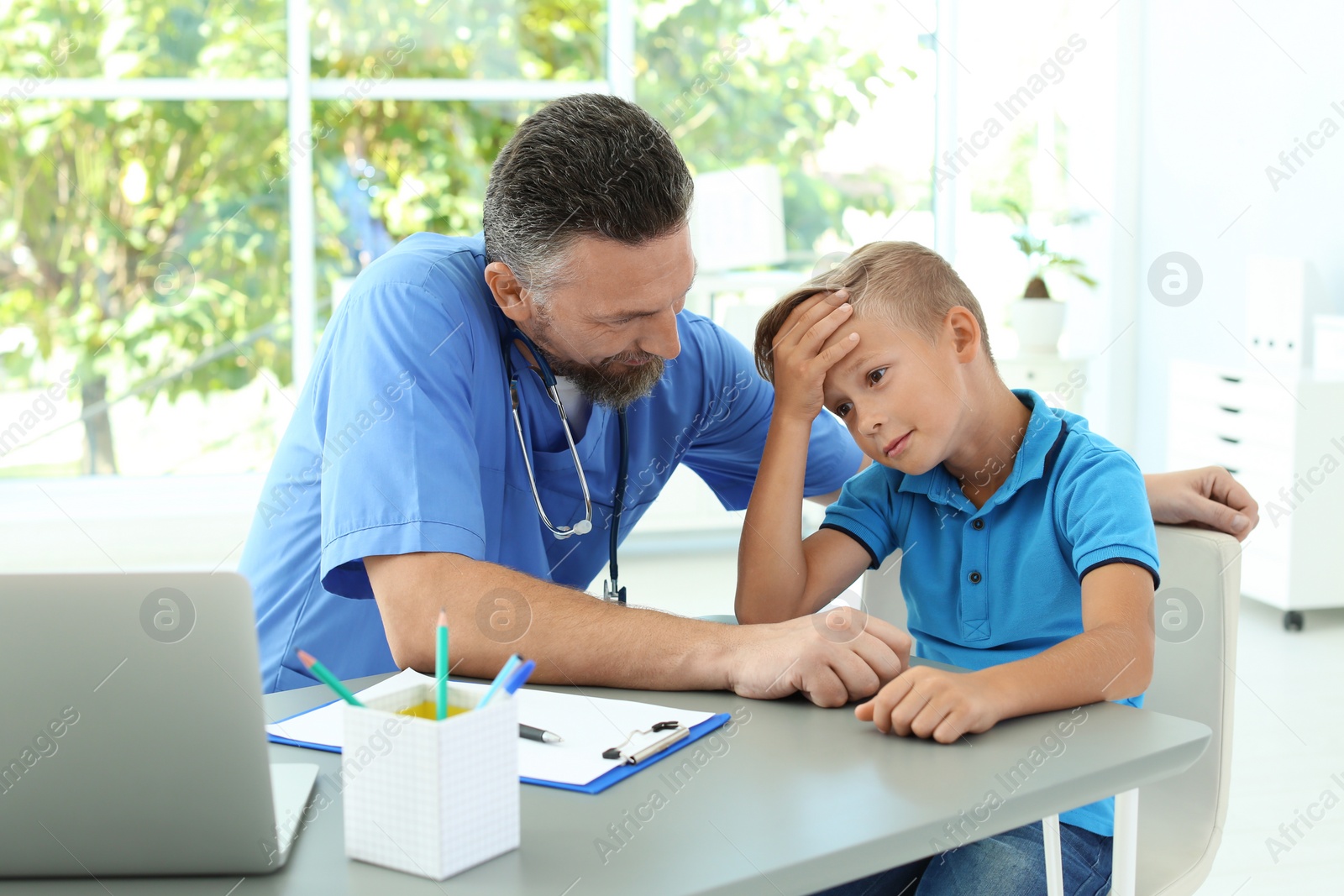 Photo of Male medical assistant consulting child in clinic