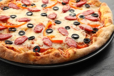 Tasty pizza with cheese, dry smoked sausages, olives and pepper on grey table, closeup