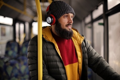 Mature man with headphones listening to music in public transport