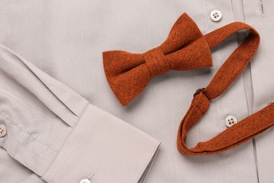 Photo of Stylish terracotta bow tie on beige shirt, top view