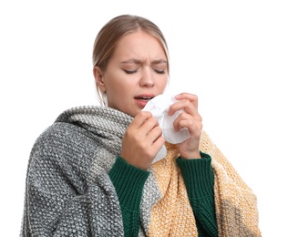 Young woman wrapped in warm blanket suffering from cold on white background