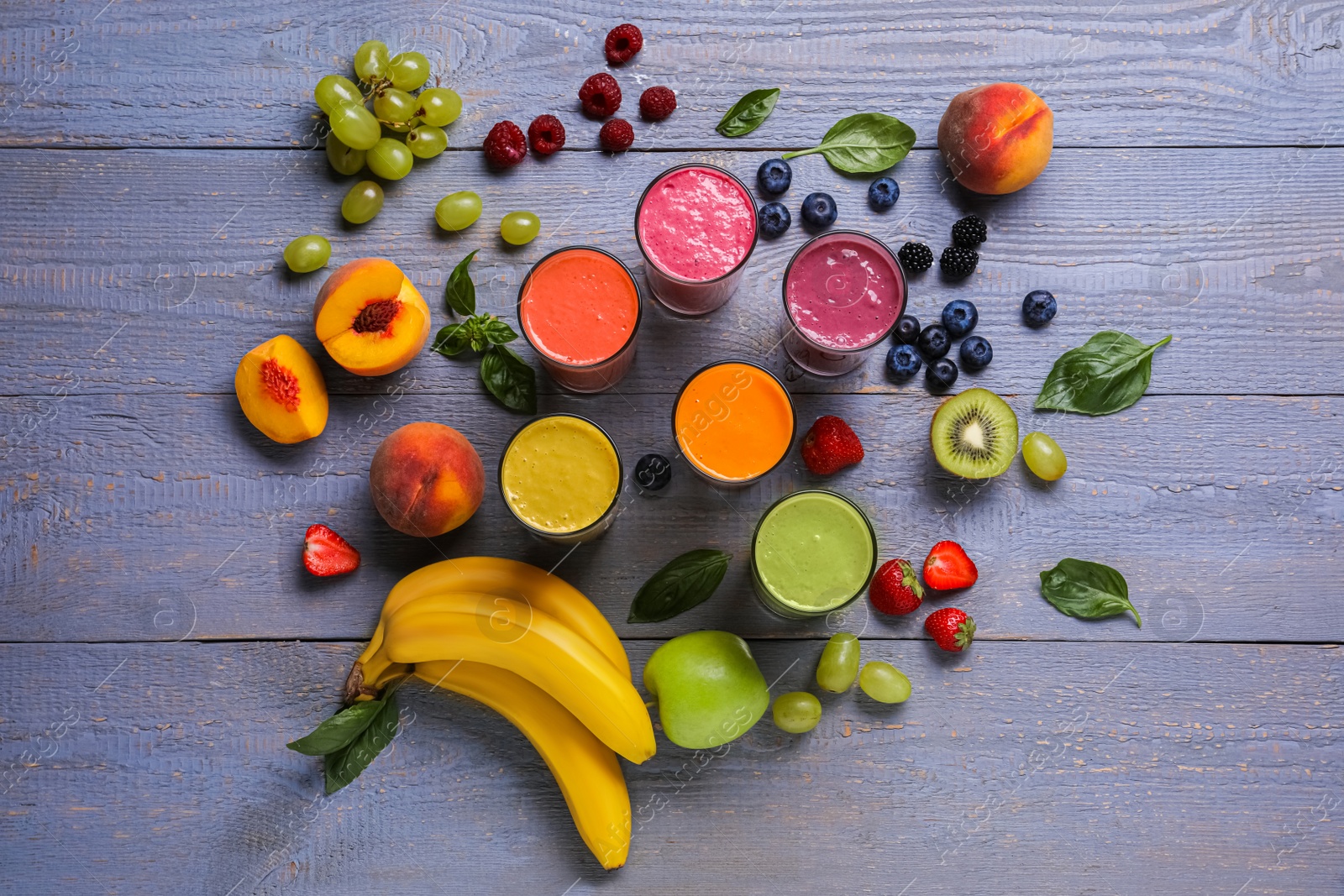 Photo of Many different delicious smoothies and ingredients on grey wooden table, flat lay