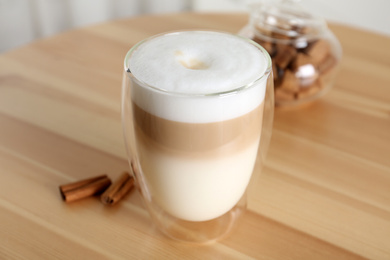 Photo of Delicious latte macchiato in glass on wooden table