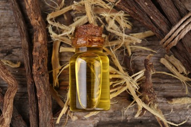Photo of Dried sticks of licorice root and essential oil on wooden table, flat lay