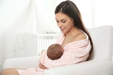 Photo of Young woman breastfeeding her baby in nursery. Space for text