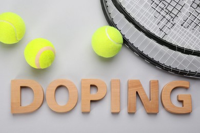 Photo of Word Doping, tennis rackets and balls on light grey background, flat lay