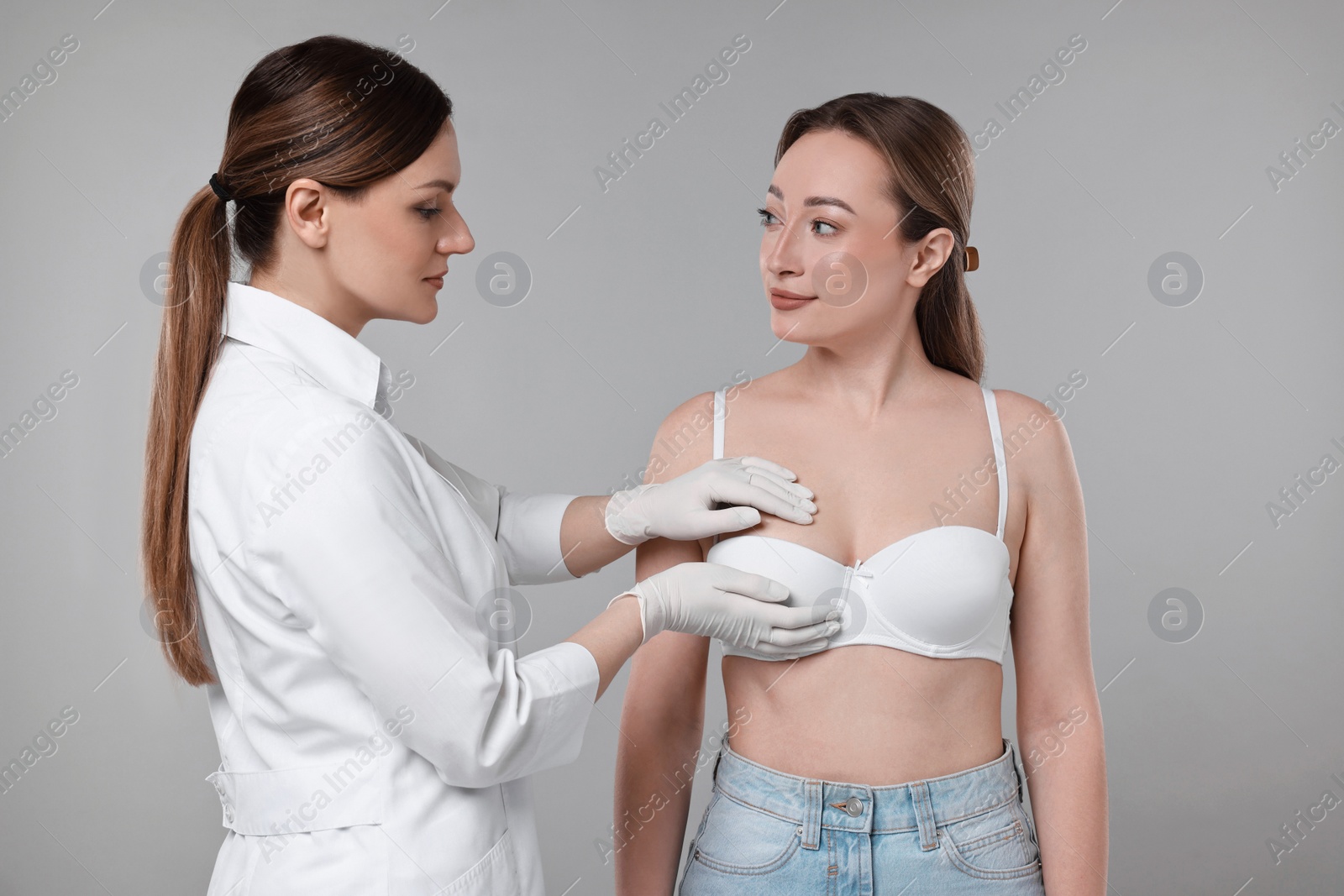 Photo of Mammologist checking woman's breast on gray background