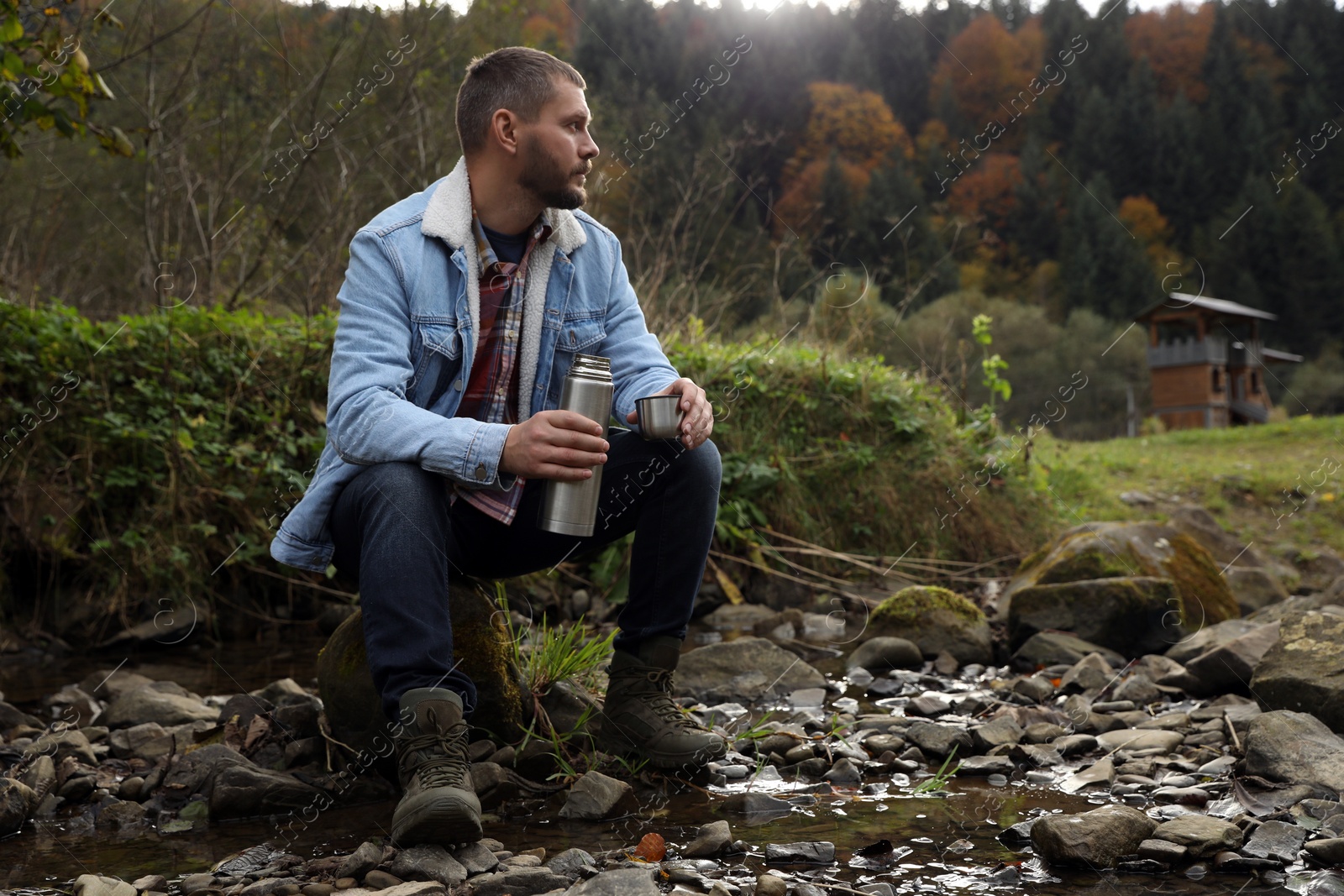 Photo of Man with metallic thermos and cup lid in nature, space for text