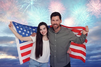 4th of July - Independence day of America. Happy father and his daughter holding national flag of United States against sky with fireworks