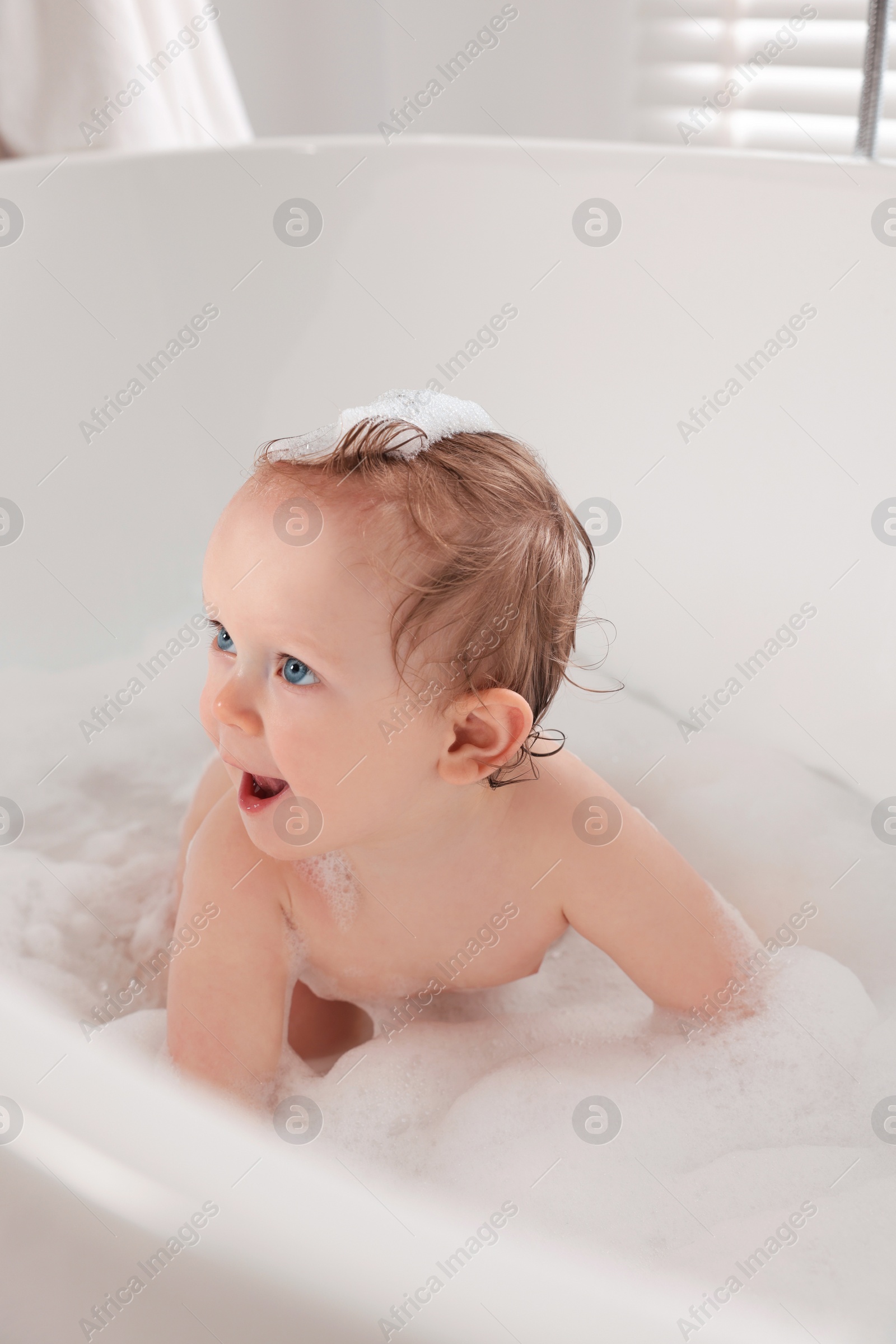 Photo of Cute little baby bathing in tub at home