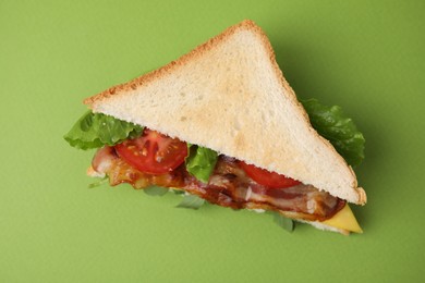Photo of Delicious sandwich with fried bacon on green background, top view