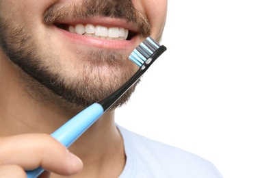 Photo of Young man with toothbrush on white background, closeup. Space for text
