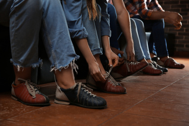 Photo of Friends putting shoes on at n bowling club, closeup of legs