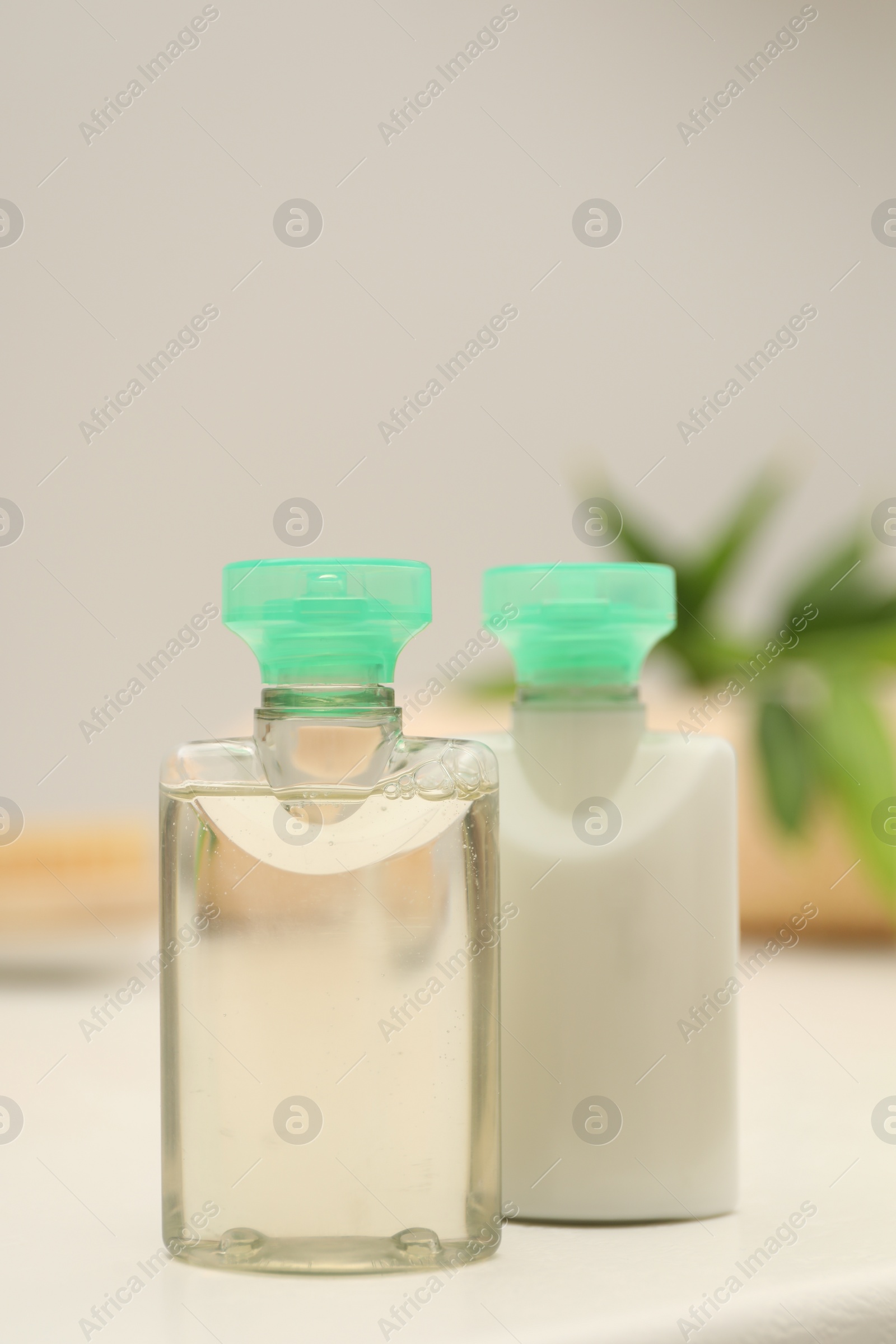 Photo of Mini bottles of cosmetic products on white table against blurred background