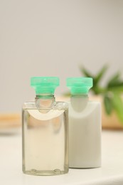 Photo of Mini bottles of cosmetic products on white table against blurred background