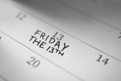 Photo of Calendar page with phrase Friday The 13th, closeup. Superstition of bad luck