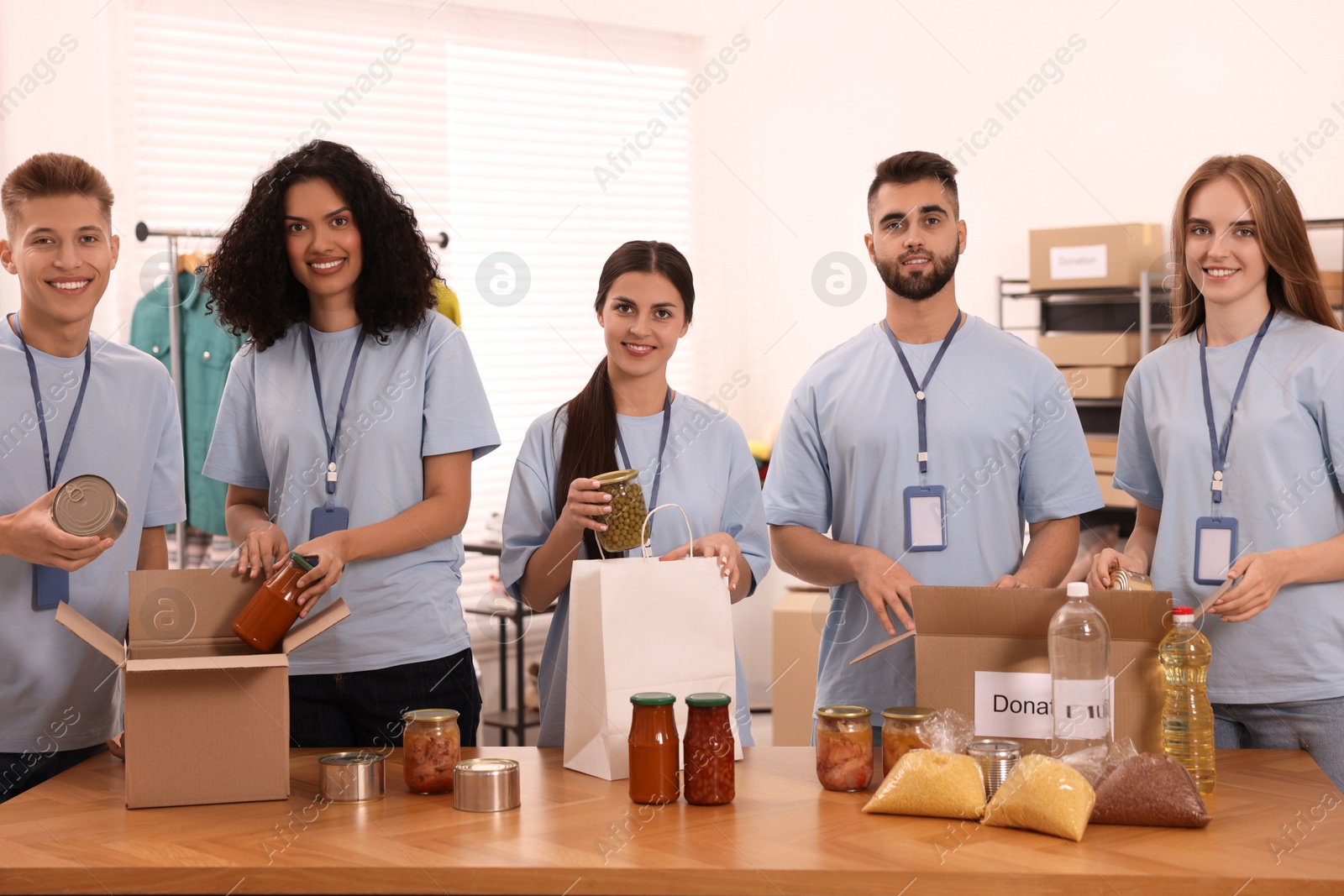 Photo of Portrait of volunteers packing food products at table in warehouse