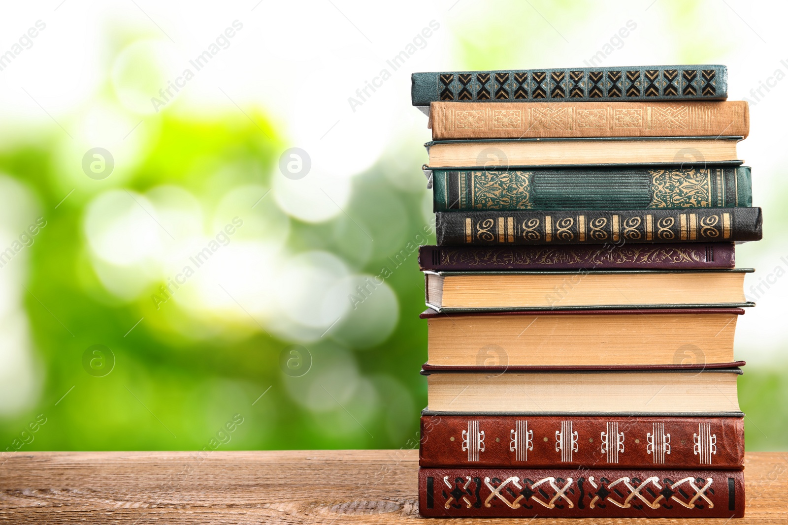 Image of Collection of different books on wooden table against blurred green background, space for text