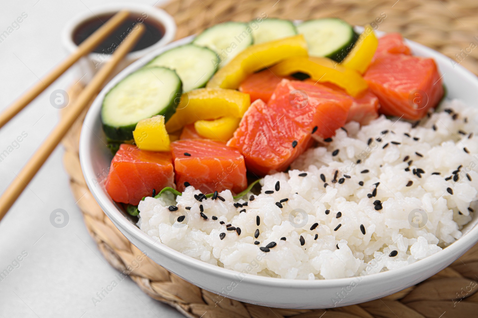 Photo of Delicious poke bowl with salmon, rice and vegetables on white table, closeup