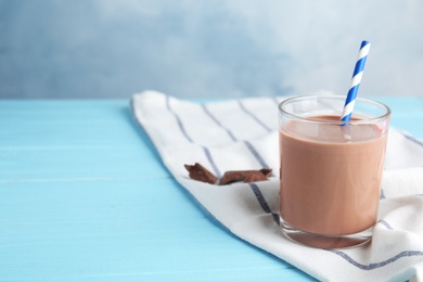 Photo of Glass with tasty chocolate milk on wooden table, space for text. Dairy drink