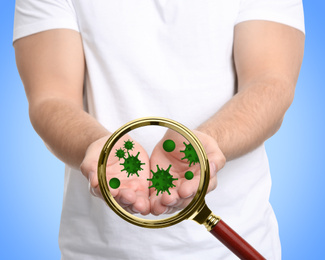 Image of Detecting bacteria with magnifying glass on blue background, closeup. Prevention disease