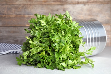 Photo of Tin can with fresh green parsley on table