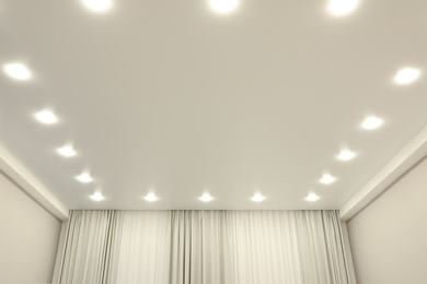 Photo of White stretch ceiling with spot lights in room