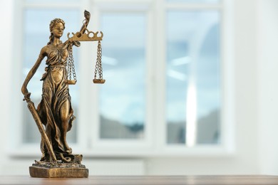 Figure of Lady Justice and gavel on table indoors, space for text. Symbol of fair treatment under law