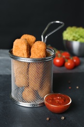Photo of Slate plate with basket of cheese sticks and sauce on table