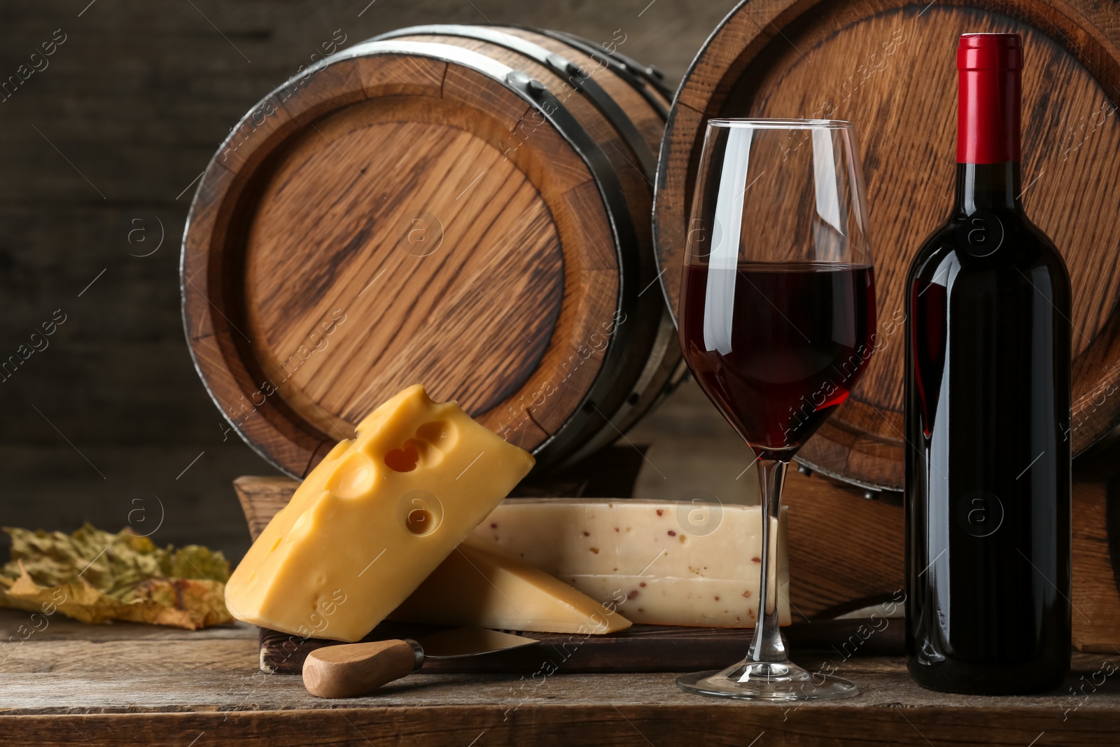 Photo of Winemaking. Tasty wine, barrels and cheese on wooden table