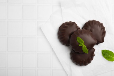 Photo of Delicious chocolate covered zephyrs with mint on white table, flat lay. Space for text
