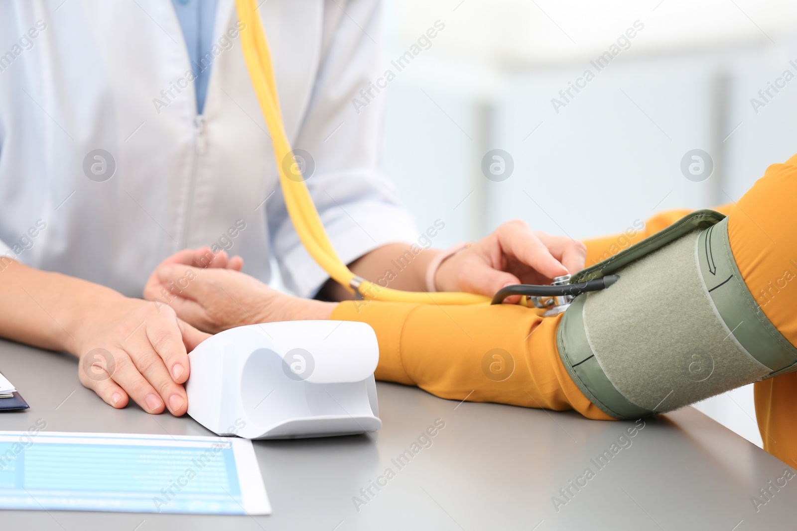 Photo of Doctor measuring blood pressure of elderly patient in hospital, closeup