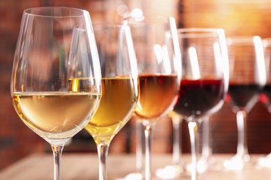 Different tasty wines in glasses against blurred background