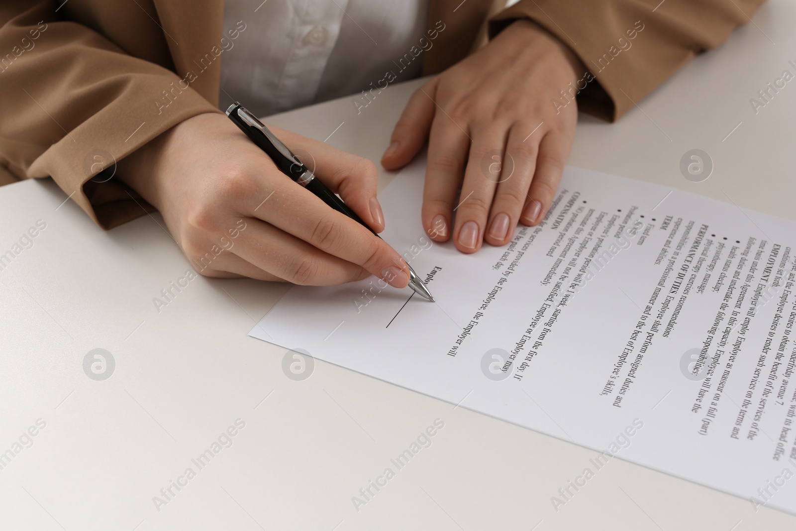 Photo of Businesswoman signing contract at white table, closeup of hands