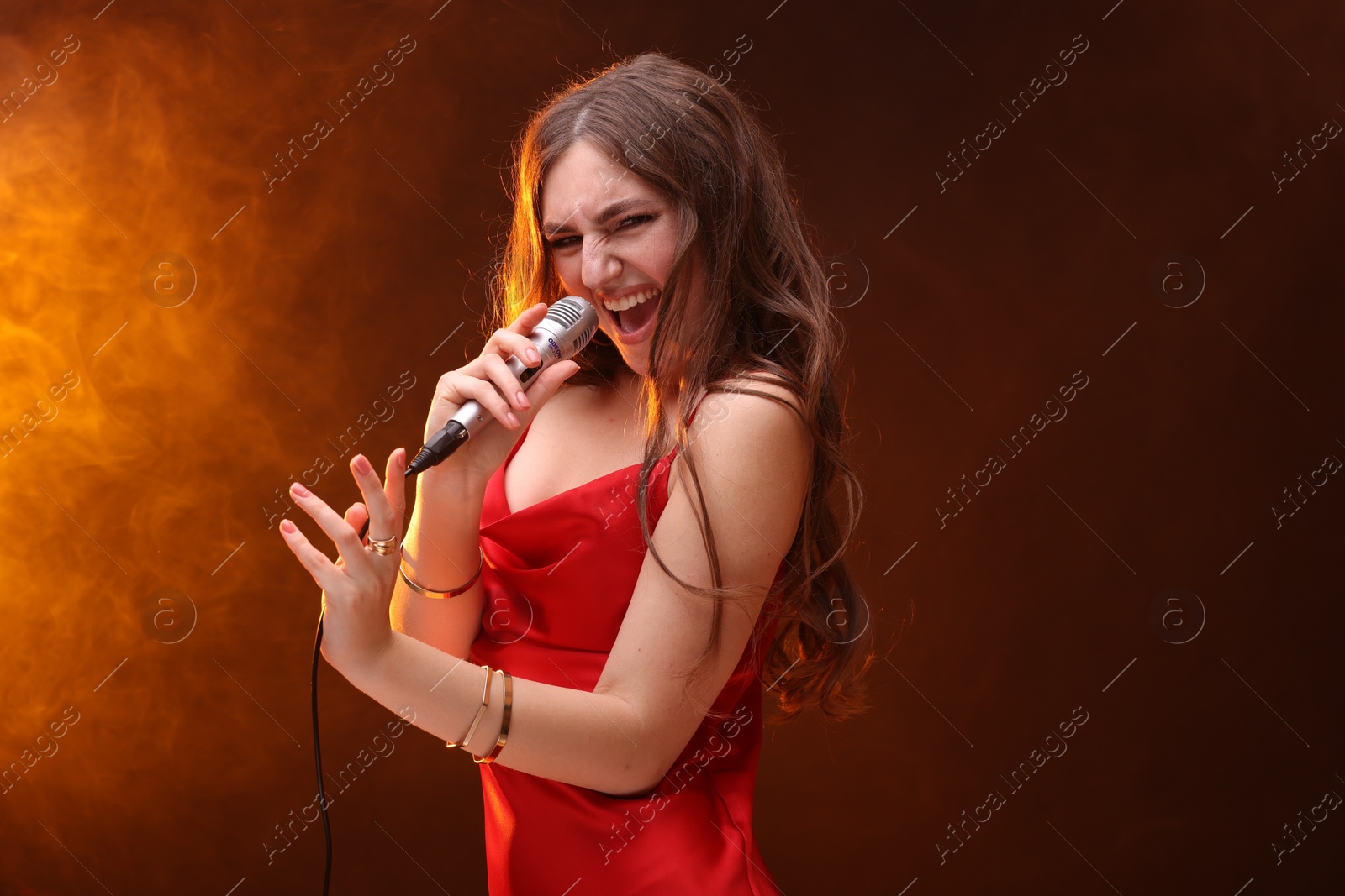 Photo of Emotional woman with microphone singing in color lights