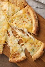 Delicious cut cheese pizza on wooden table, top view