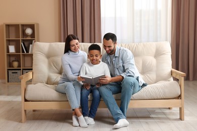Happy international family reading book on sofa at home