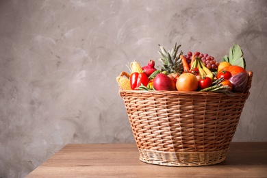 Assortment of fresh organic fruits and vegetables in basket on wooden table. Space for text