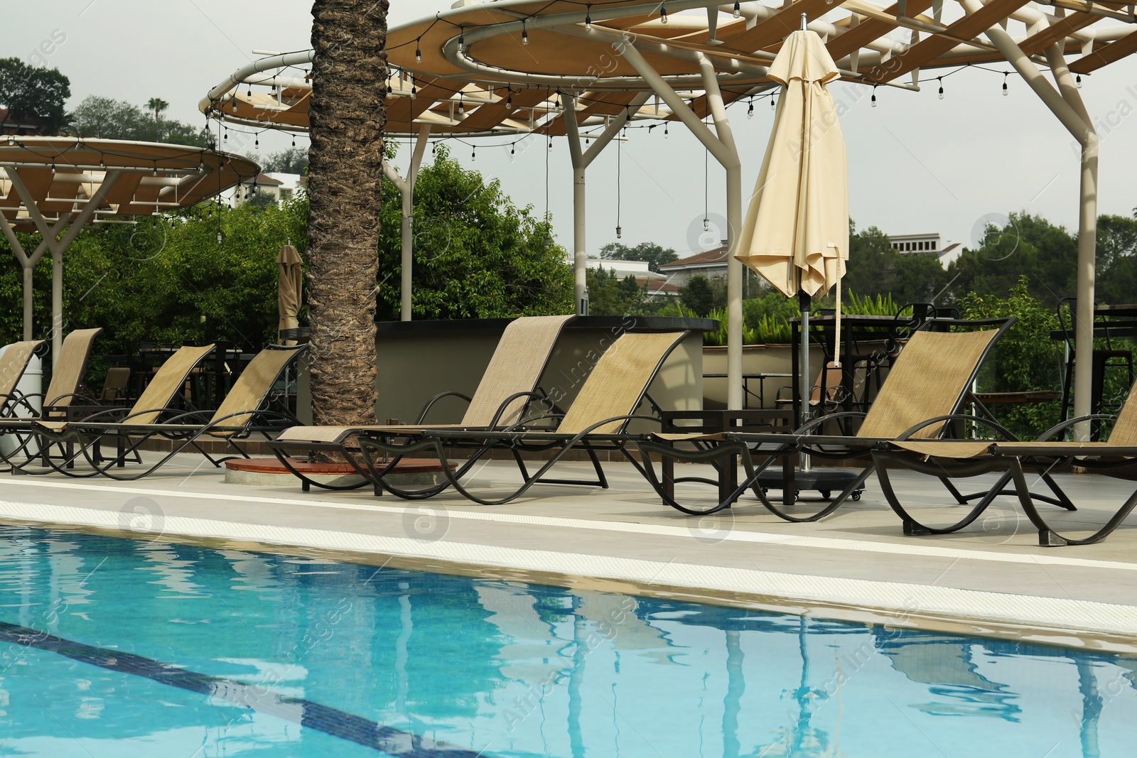 Photo of Sunbeds near swimming pool at luxury resort