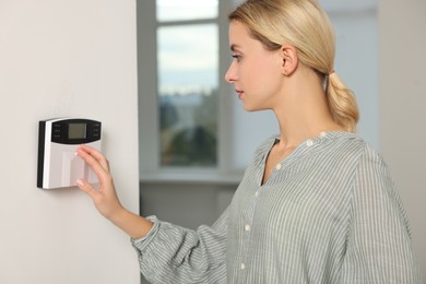 Photo of Woman using home security alarm system indoors