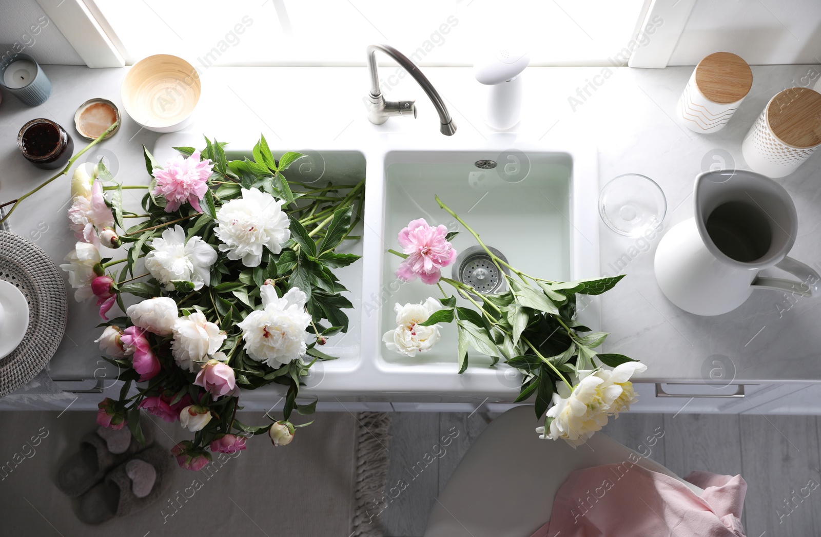 Photo of Bunch of beautiful peonies in kitchen sink, above view