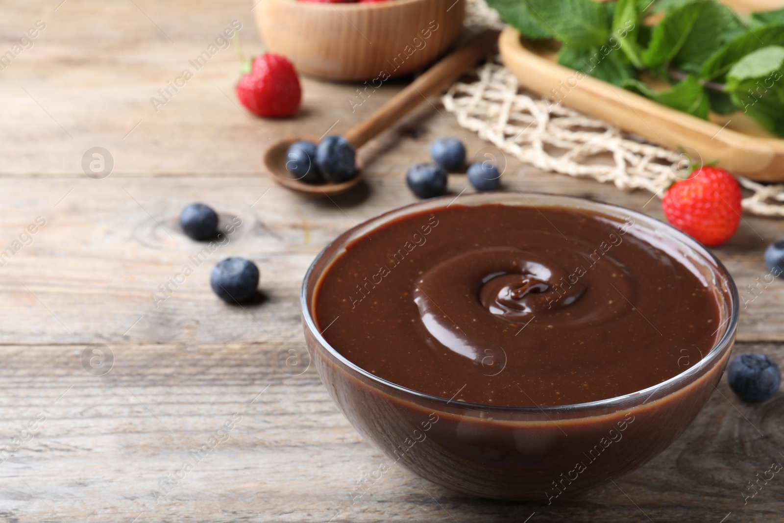 Photo of Delicious chocolate cream and berries on wooden table, space for text