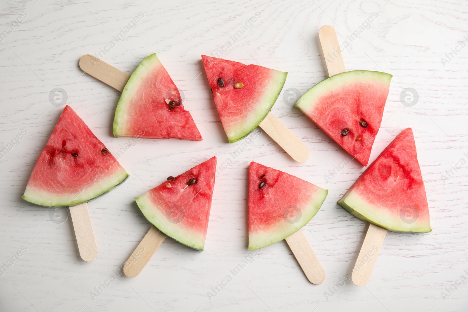 Photo of Watermelon slices with wooden sticks on white background, flat lay