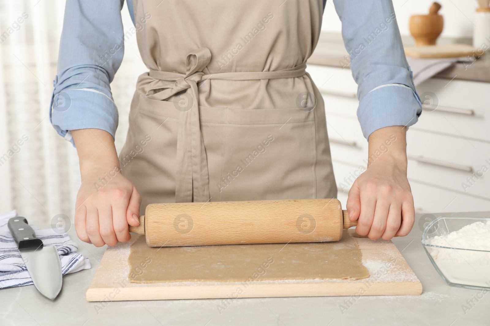 Photo of Woman making soba (buckwheat noodles) at light marble table in kitchen, closeup