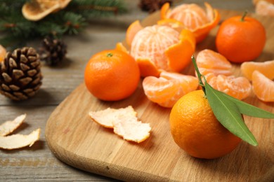Photo of Fresh tangerines and fir cones on wooden table, closeup. Christmas atmosphere