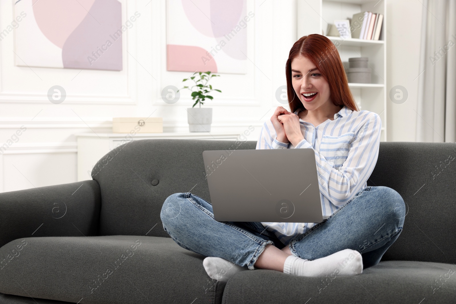 Photo of Happy woman with laptop sitting on couch in room