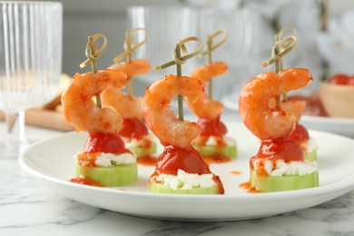 Tasty canapes with shrimps, vegetables and cream cheese on white marble table, closeup